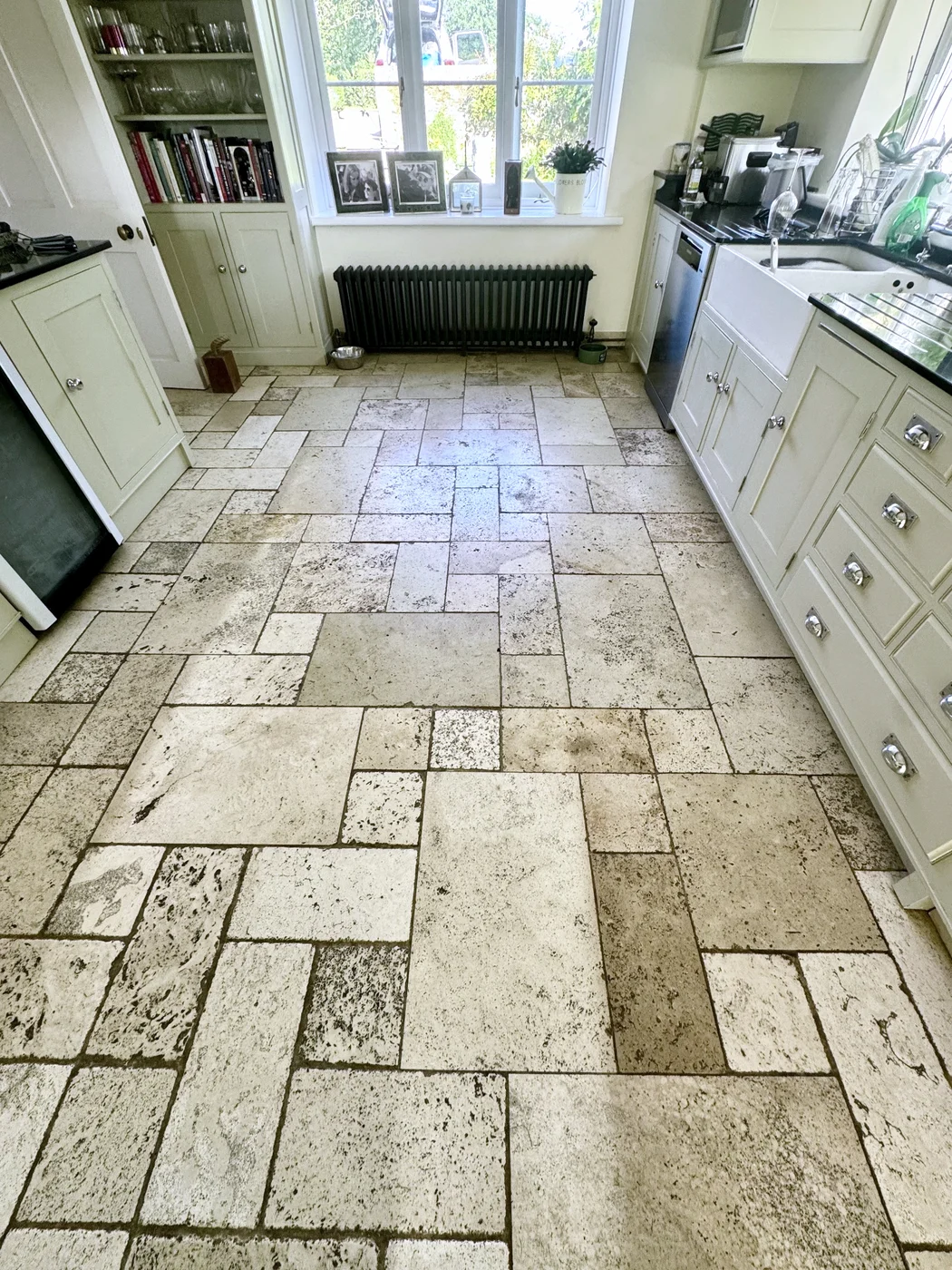 Cream kitchen with patterned floor tiles and dark grout lines before restoration