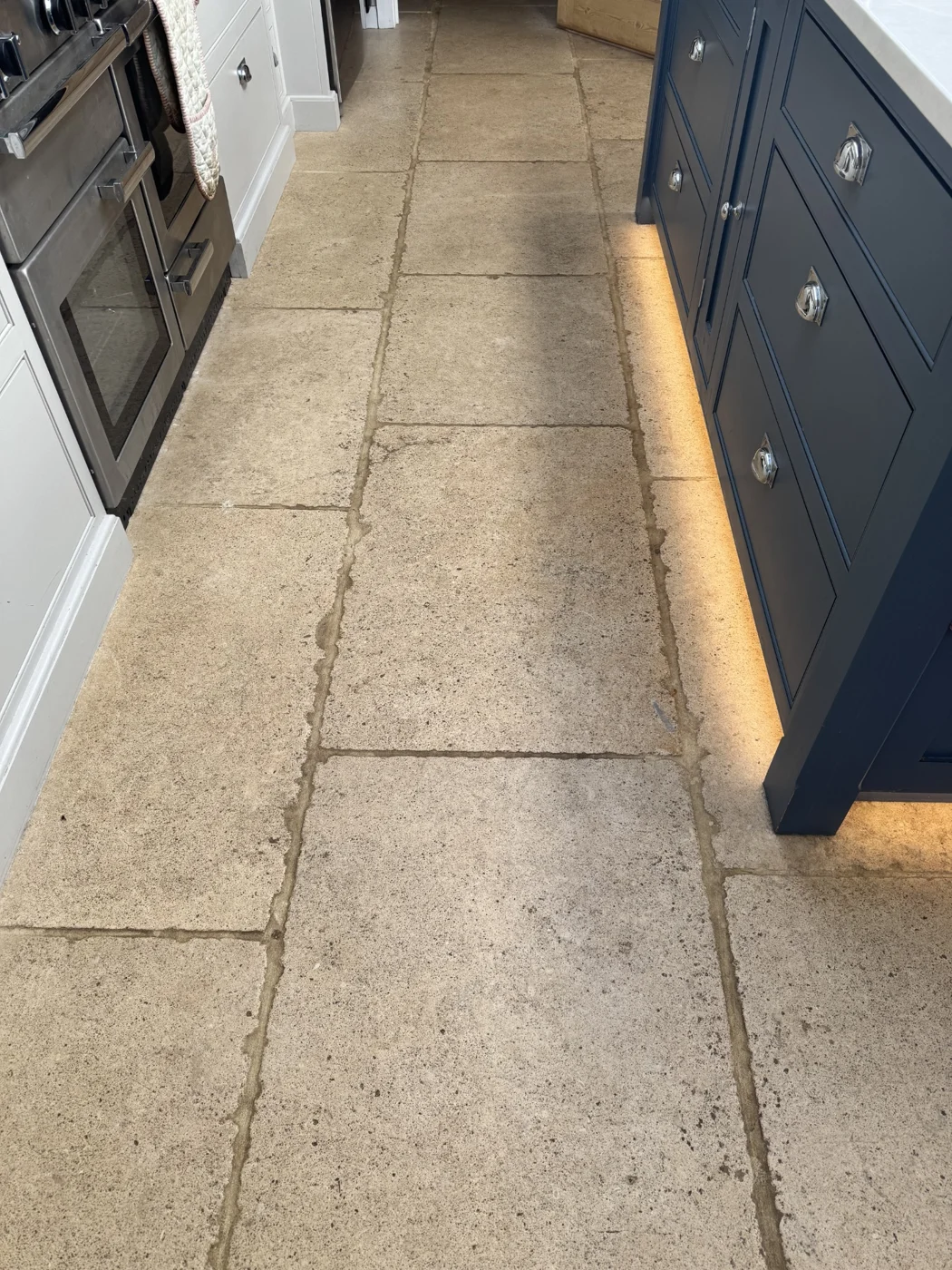 Kitchen floor before restoration, with dark grout lines and an uneven appearance