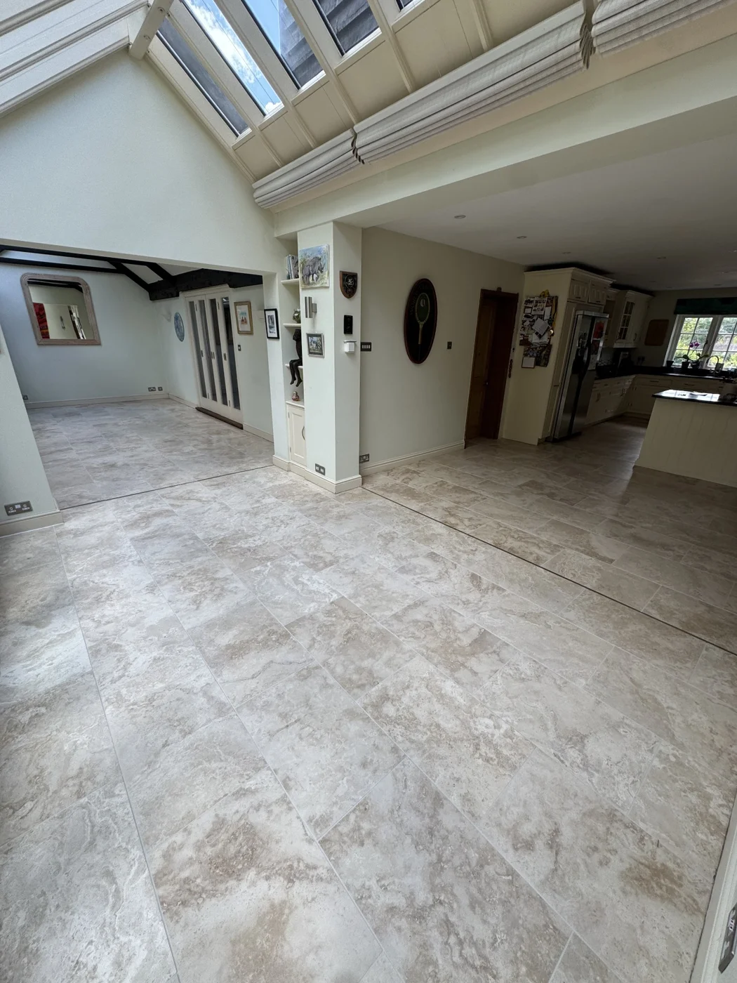 Wider view of the same tiled floor extending through an open-plan kitchen